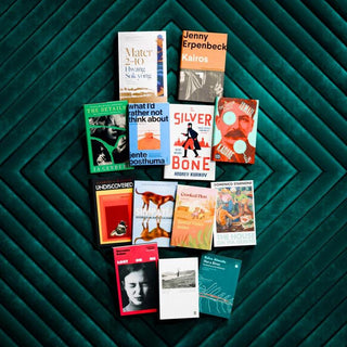 Flatlay photo of the Booker Prize 2024 International Longlist books on a velvet emerald green background